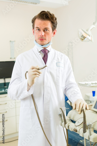 Photo: Dentist in his surgery, he holds a drill Dentist in his surgery, he holds a drill
