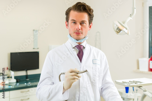 Photo: Dentist in his surgery, he holds a drill Dentist in his surgery, he holds a drill