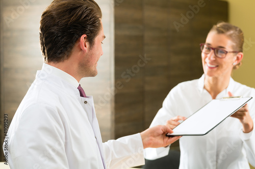 Photo: Dentist and nurse with clipboard in clinic Dentist and nurse with clipboard in clinic