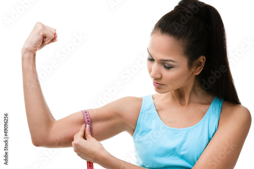 Photo: Sportive woman measures her bicep with measuring tape Sportive woman measures her bicep with measuring tape