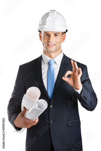Photo: Engineer in hard hat hands blueprints and gestures Okay Engineer in hard hat hands blueprints and gestures Okay