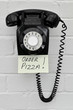 Black retro telephone with reminder note to order pizza