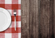 white plate and fork on old wooden table with red checked tablec