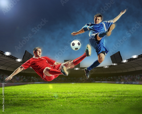 Photo: two football players striking the ball two football players striking the ball