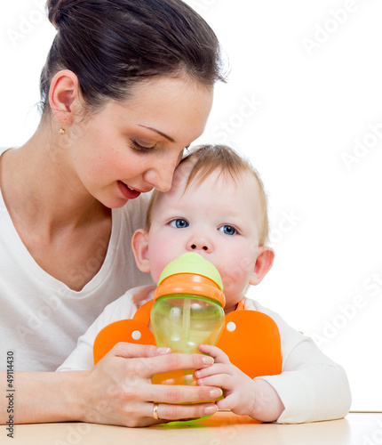 Photo: young mother giving drink to baby from feeding cup young mother giving drink to baby from feeding cup