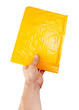 Hand holding yellow mail package, isolated on white