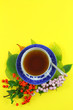 Autumn leaves and cup of tea on yellow background
