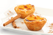 Custard Pies over a white plate with cinnamon sticks