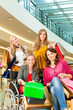 Four female friends shopping in a mall with wheelchair