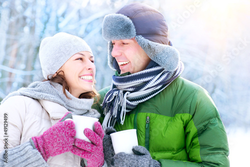 Photo: Happy Couple with Hot Drinks Outdoors. Winter Vacation Happy Couple with Hot Drinks Outdoors. Winter Vacation