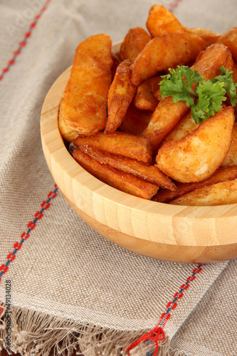 Photo: Appetizing village potatoes in bowl on wooden table close-up Appetizing village potatoes in bowl on wooden table close-up