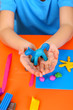 Child's hands holding hand-made plasticine hourse over desk