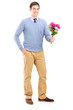 Full length portrait of a young romantic man holding a bouquet o