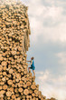 Challenge - Young man climbing the large pile of cut wooden logs
