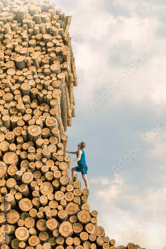 Photo: Challenge - Young man climbing the large pile of cut wooden logs Challenge - Young man climbing the large pile of cut wooden logs