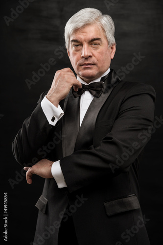 Photo: Portrait of handsome mature business leader over black backgroun Portrait of handsome mature business leader over black backgroun