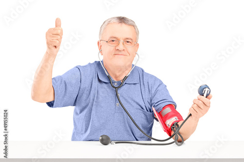Photo: Happy senior man with blood pressure cuff and giving a thumb up Happy senior man with blood pressure cuff and giving a thumb up