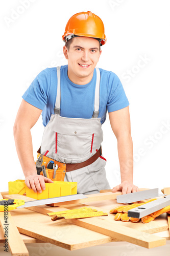 Photo: Manual woker standing next to a table with equipment and wooden Manual woker standing next to a table with equipment and wooden