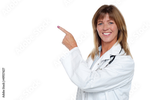 Photo: Cheerful female doctor pointing away Cheerful female doctor pointing away