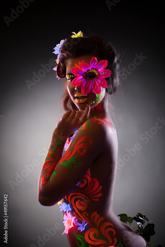 Photo: Pretty young woman in glowing flowers - uv light Pretty young woman in glowing flowers - uv light