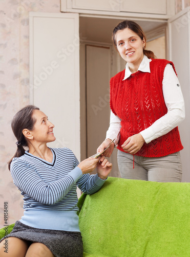 Photo: woman gives money to her mature mother woman gives money to her mature mother