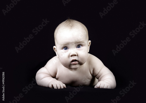 Photo: Four months baby on the dark background Four months baby on the dark background