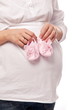 Foto: Pregnant woman keeping pink baby-shoes. Pregnant woman keeping pink baby-shoes.