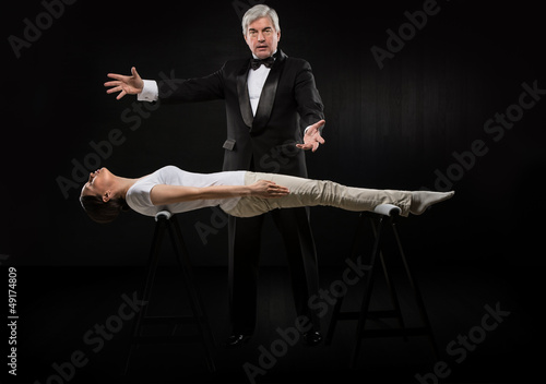 Photo: Portrait of professional hypnotist on black background working w Portrait of professional hypnotist on black background working w