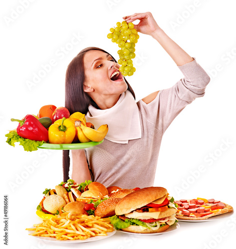 Photo: Woman choosing between fruit and hamburger. Woman choosing between fruit and hamburger.