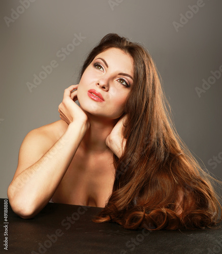 Photo: A beautiful woman touching her face isolated on grey background A beautiful woman touching her face isolated on grey background