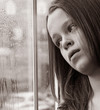 Stunning photo of a young girl gazing through a rainy window