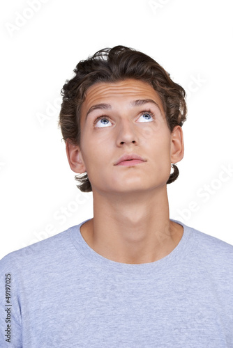 Photo: Wide-eyed young guy looking upwards against a white background Wide-eyed young guy looking upwards against a white background