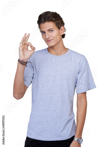 Photo: Young guy giving the OK-sign while smiling against a white backg Young guy giving the OK-sign while smiling against a white backg