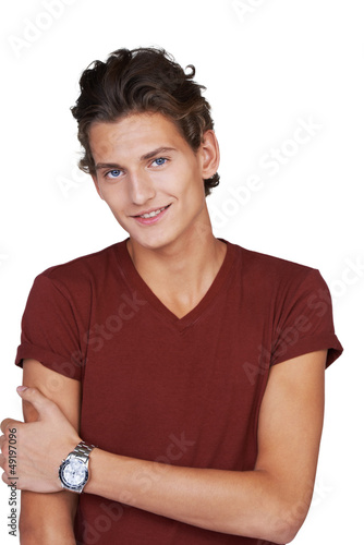 Photo: Smiling young guy holding his arm against himself and looking at Smiling young guy holding his arm against himself and looking at