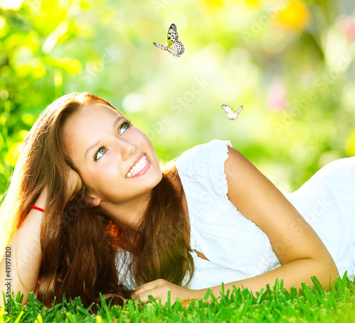 Photo: Spring Beauty. Beautiful Girl Lying on Green Grass outdoor Spring Beauty. Beautiful Girl Lying on Green Grass outdoor