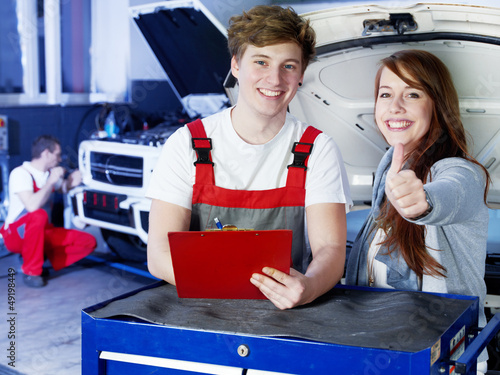 Photo: Motor mechanics and customer in garage show thumbs up Motor mechanics and customer in garage show thumbs up