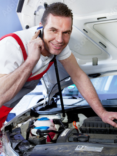 Photo: Car mechanic calls a customer to tell him the repair costs Car mechanic calls a customer to tell him the repair costs