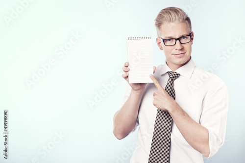 Photo: Smiling businessman pointing finger at blank notebook. Smiling businessman pointing finger at blank notebook.