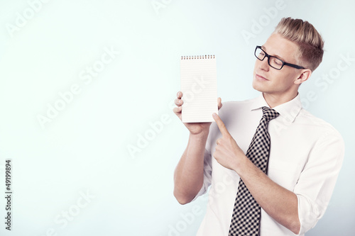 Photo: Businessman looking and pointing finger at empty notepad. Businessman looking and pointing finger at empty notepad.