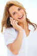 Lovely blonde female wearing a white shirt speaking happily on h