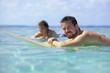 Surfer giving you a broad smile while floating on his surfboard 