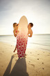 Photo: Cute young couple playing peek-a-boo around a surfboard Cute young couple playing peek-a-boo around a surfboard