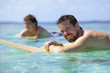 Surfer giving you a broad smile while floating on his surfboard 