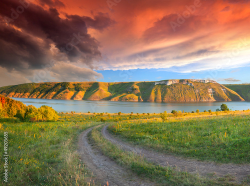 Photo: Dramatic summer landscape with the river in the mountains. Sunse Dramatic summer landscape with the river in the mountains. Sunse