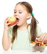 Little girl choosing between apples and sweets