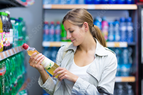 Photo: Beautiful young woman shopping in a grocery store/supermarket Beautiful young woman shopping in a grocery store/supermarket