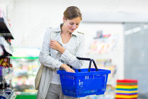 Photo: Beautiful young woman shopping in a grocery store/supermarket Beautiful young woman shopping in a grocery store/supermarket