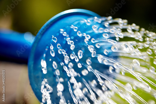 Photo: Blue watering can used to water the green grass Blue watering can used to water the green grass