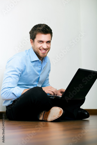 Photo: Young man sitting on the floor with his laptop Young man sitting on the floor with his laptop