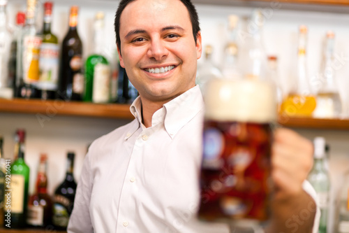 Photo: Barman offering a beer in a pub Barman offering a beer in a pub